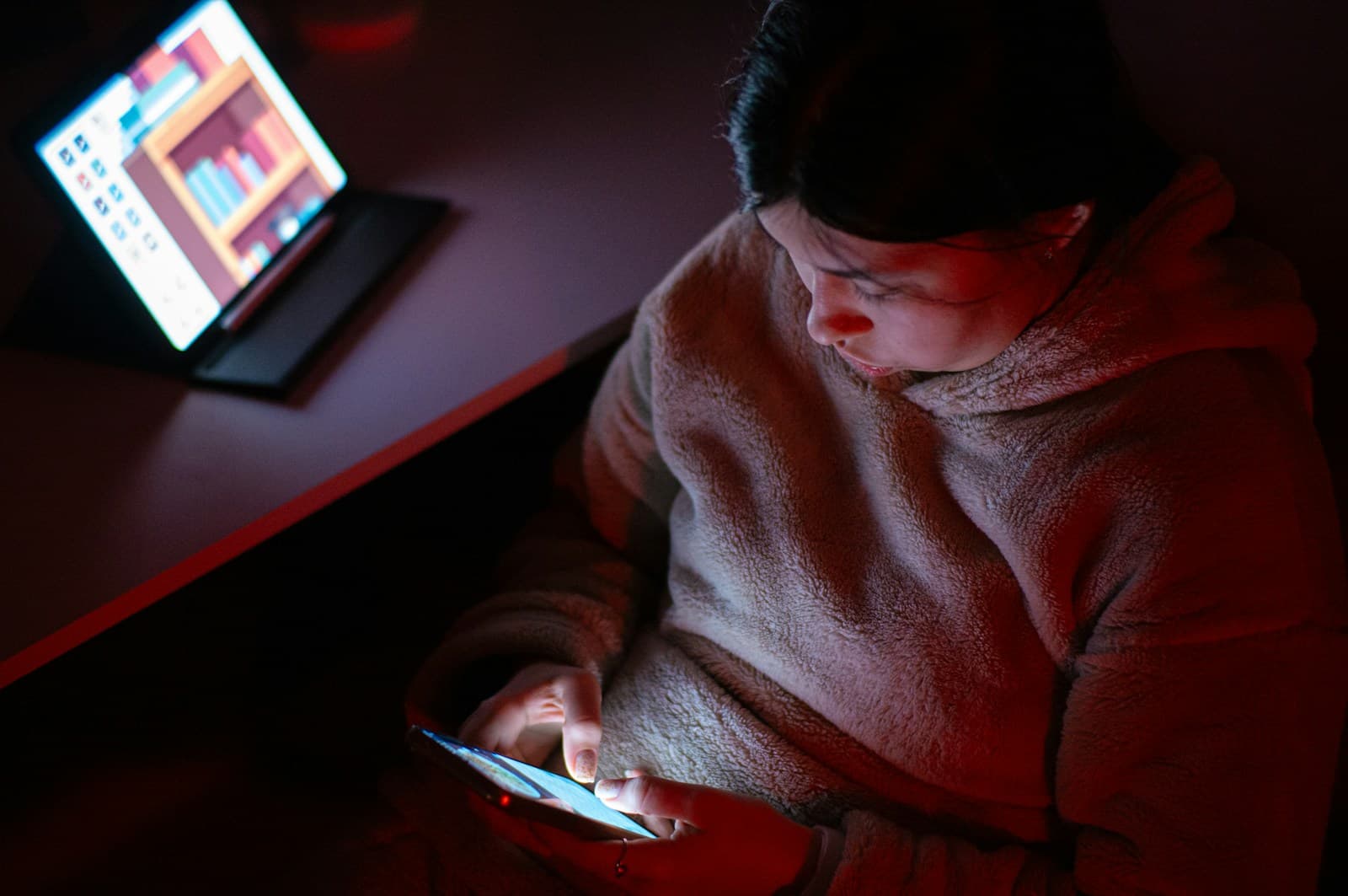 Une personne assise dans un fauteuil regarde attentivement l'écran de son téléphone.