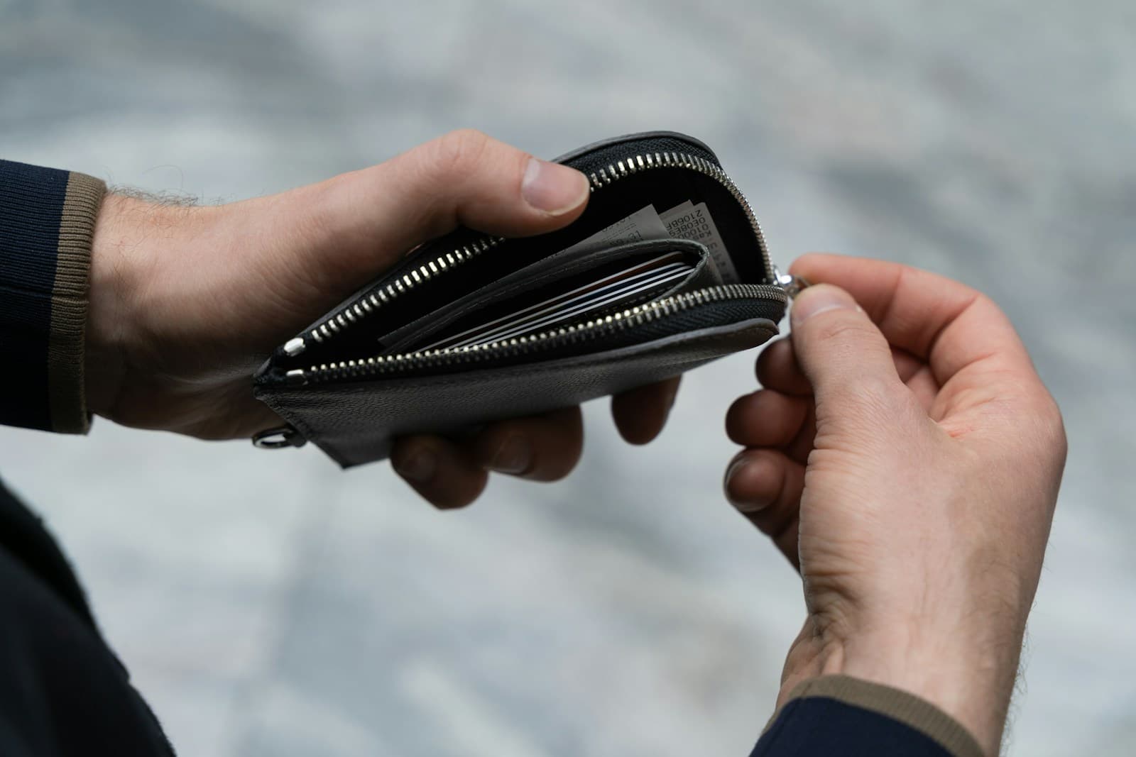 Un portefeuille en cuir ouvert entre deux mains, contenant des cartes et des billets.